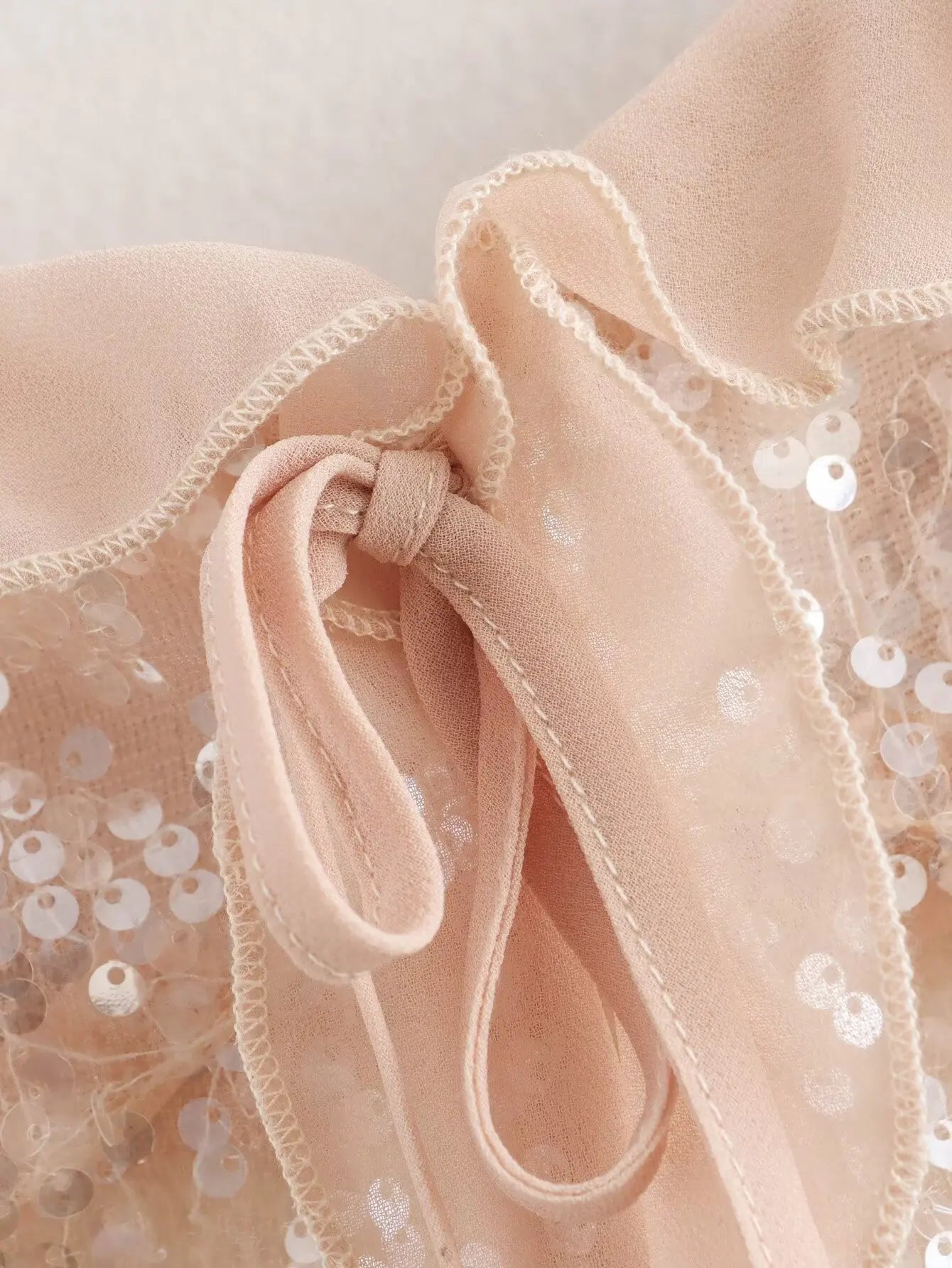 Sparkle & Satin Sequin Cami Top – Blush Nude.  Elevate your evening style with this dazzling sequin cami top in a dreamy blush nude tone. Designed with a soft satin ruffle neckline and delicate spaghetti straps