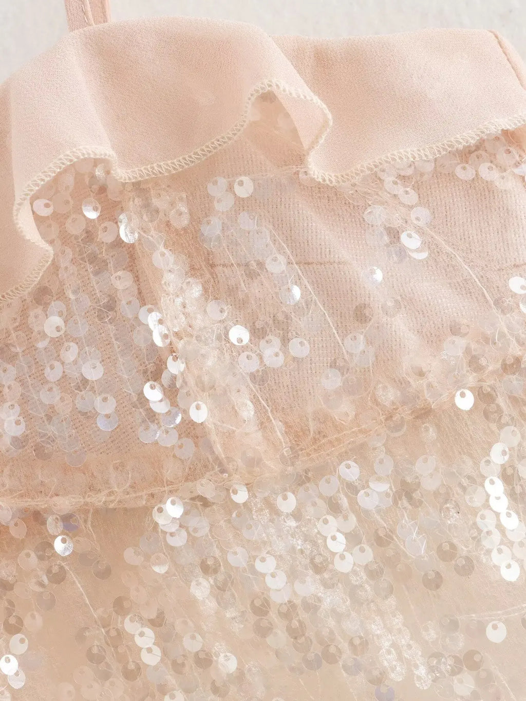 Sparkle & Satin Sequin Cami Top – Blush Nude.  Elevate your evening style with this dazzling sequin cami top in a dreamy blush nude tone. Designed with a soft satin ruffle neckline and delicate spaghetti straps