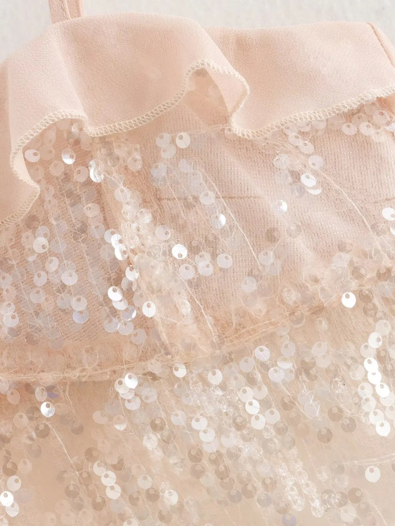 Sparkle & Satin Sequin Cami Top – Blush Nude.  Elevate your evening style with this dazzling sequin cami top in a dreamy blush nude tone. Designed with a soft satin ruffle neckline and delicate spaghetti straps